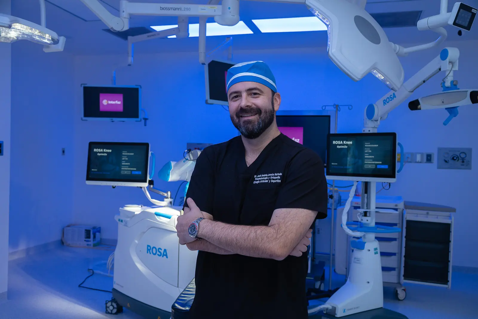 Dr. Andrés Acosta smiling in the operating room in front of the ROSA robot