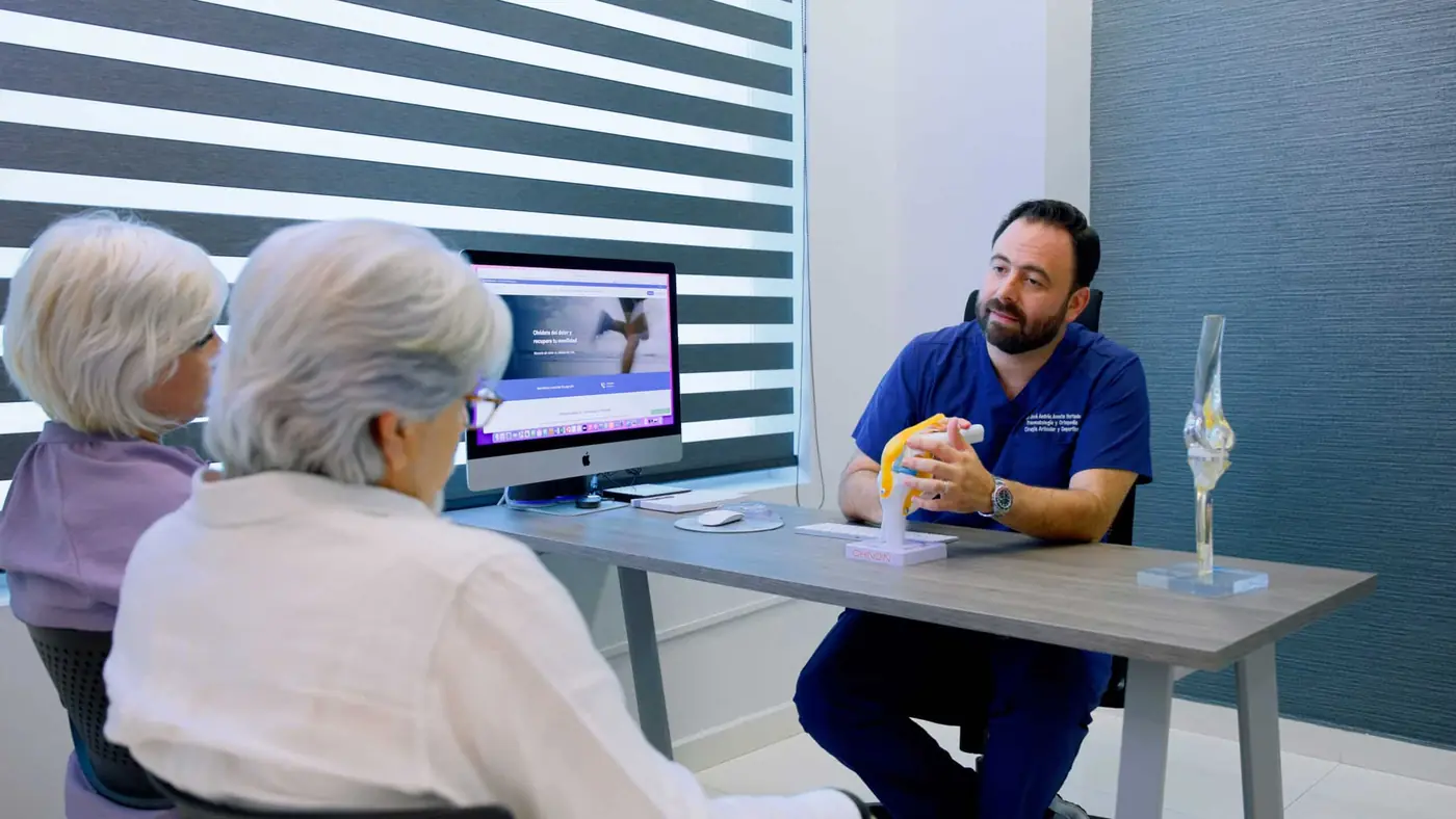 Dr. Andrés Acosta reviewing a patient's knee images with her during a consultation